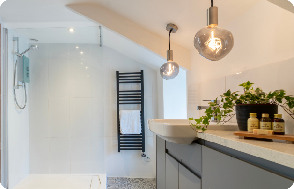 Modern bathroom with shower, stylish lighting, grey cabinets, and greenery for a fresh, minimalistic design.