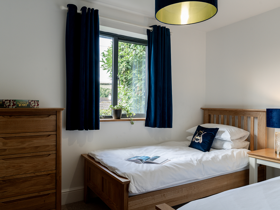 Cozy bedroom with wooden furniture, twin beds, navy curtains, and soft lighting. Perfect for a restful night's sleep.