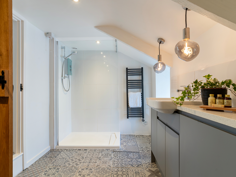 Modern bathroom with walk-in shower, patterned tiles, and pendant lighting. Relaxing, stylish, and functional space.