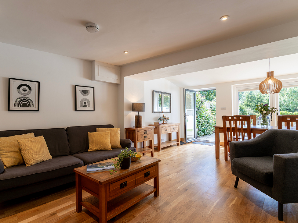 Spacious modern living room with wooden furniture, large windows, and outdoor view for home interior inspiration.