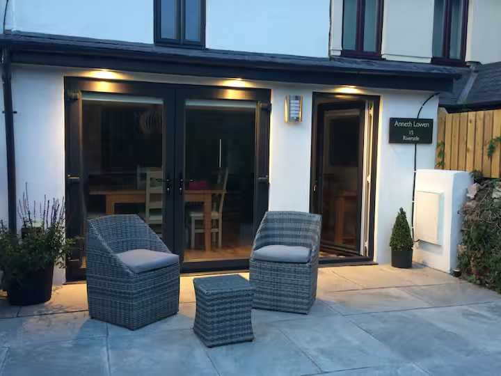 Cozy patio with wicker furniture and evening lighting by a modern glass door entrance.
