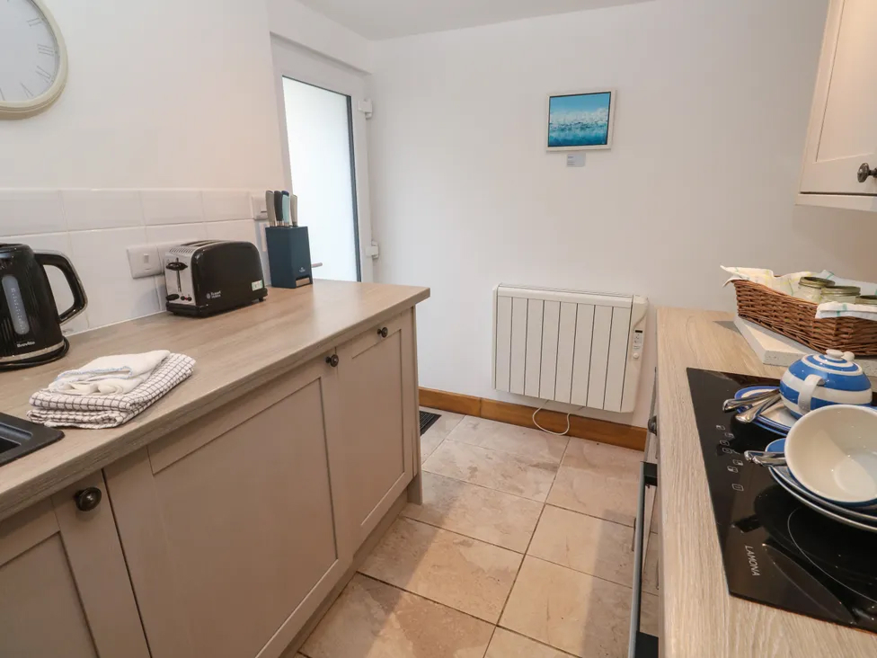 Cozy kitchen with modern appliances, including a kettle, toaster, and induction cooktop, on a wooden counter.