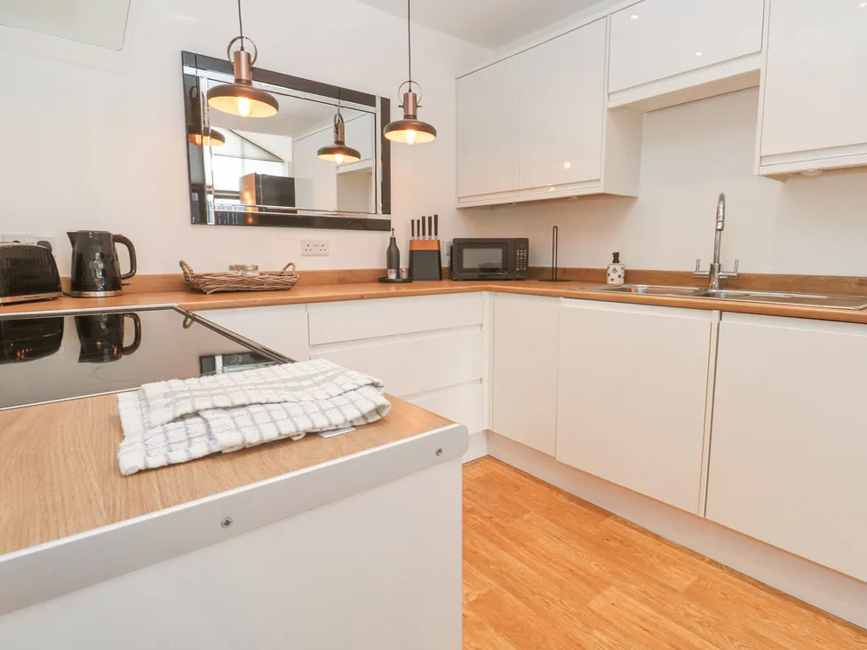 Modern kitchen with white cabinets, wood countertops, stainless steel sink, and appliances; warm lighting creates cozy